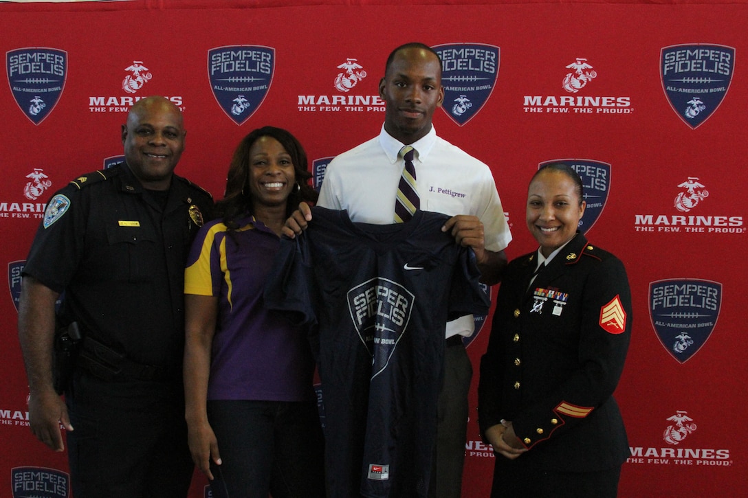 Sergeant Felicia Tanksley, a canvassing recruiter with Recruiting Sub-Station New Orleans, poses for a photo with Jamal Pettigrew and his parents during his jersey presentation held at Saint Augustine High School on Oct. 12, 2015. Pettigrew will be participating in the 2016 Semper Fidelis All-American bowl held in California on Jan. 3, 2016. For more information about the Semper Fi Bowl, visit www.semperfidelisfootball.com