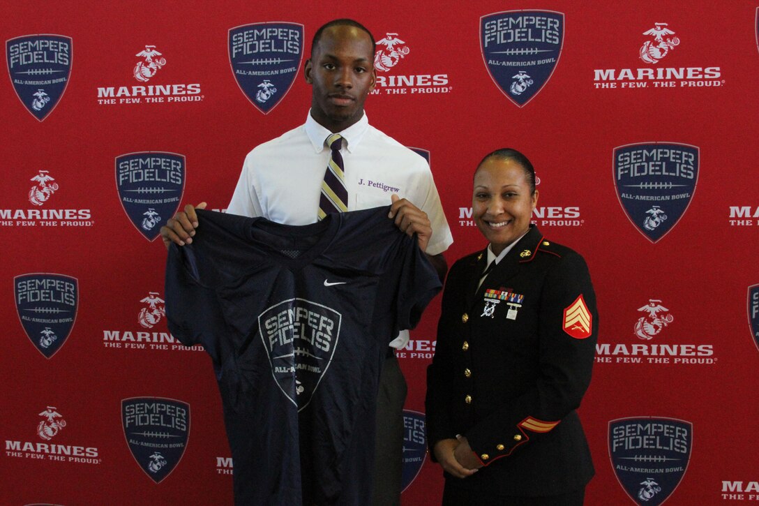 Sergeant Felicia Tanksley, a canvassing recruiter with Recruiting Sub-Station New Orleans, presents a Semper Fidelis All-American Bowl jersey to Jamal Pettigrew, a tight end for Saint Augustine High School on Oct. 12, 2015. The jersey presentation represents Pettigrew’s acceptance to play in 2016 Semper Fidelis All-American bowl on Jan. 3, 2016. 