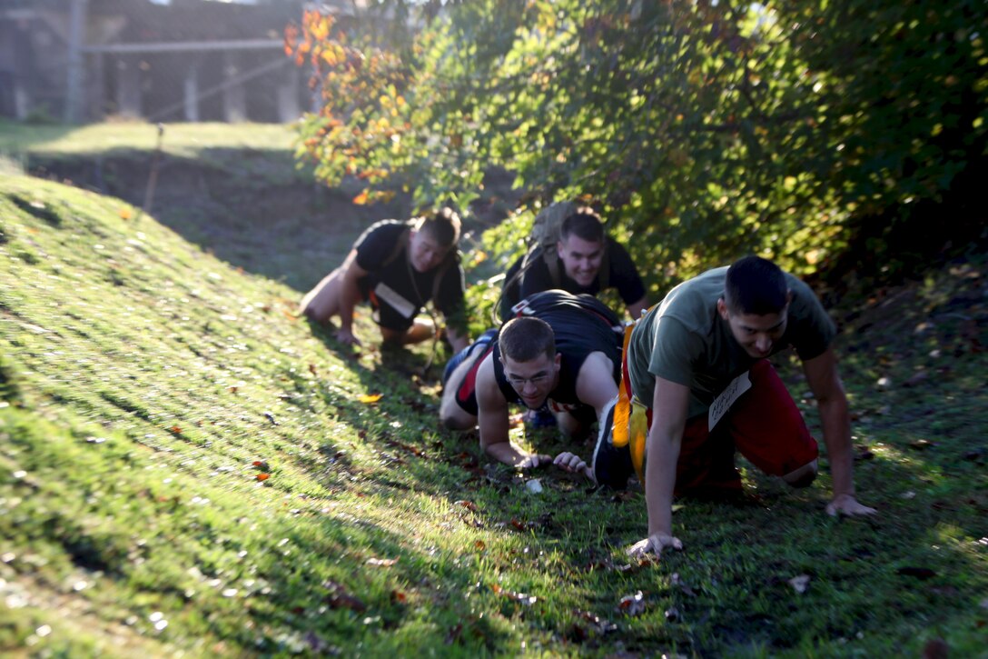 A team of service members low crawl through a ditch during the annual Marine Special Operations Command All-Terrain Competition at Marine Corps Air Station Cherry Point, N.C., Oct. 30, 2015. Eleven teams of Marines and Sailors from the air station competed in the more than seven-mile competition. The first place winners were the Marine Aviation Logistics Squadron 14 Honey Badgers. (U.S. Marine Corps Photo by Lance Cpl. Jason Jimenez/Released)