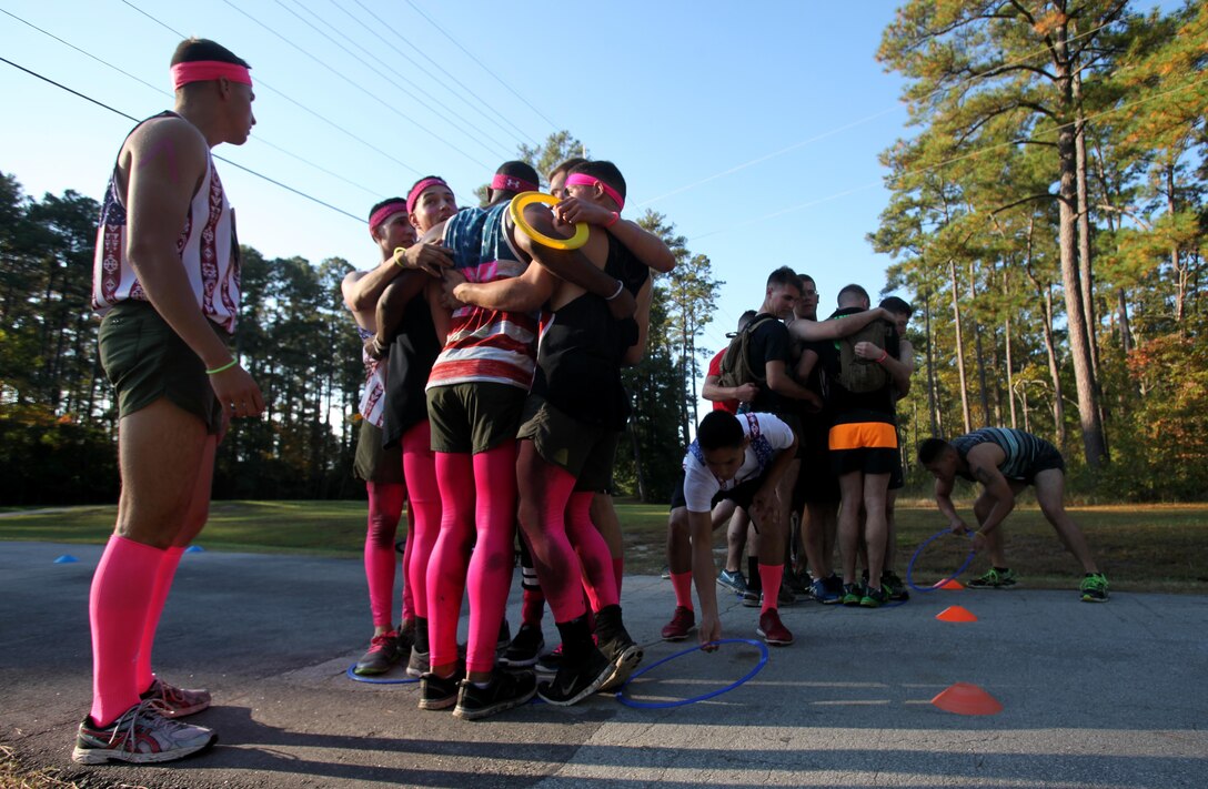 A team of service members huddle close to each other to complete a challenge during the annual Marine Special Operations Command All-Terrain Competition at Marine Corps Air Station Cherry Point, N.C., Oct. 30, 2015. Eleven teams of Marines and Sailors from the air station competed in the more than seven-mile competition. The first place winners were the Marine Aviation Logistics Squadron 14 Honey Badgers. (U.S. Marine Corps Photo by Lance Cpl. Jason Jimenez/Released)