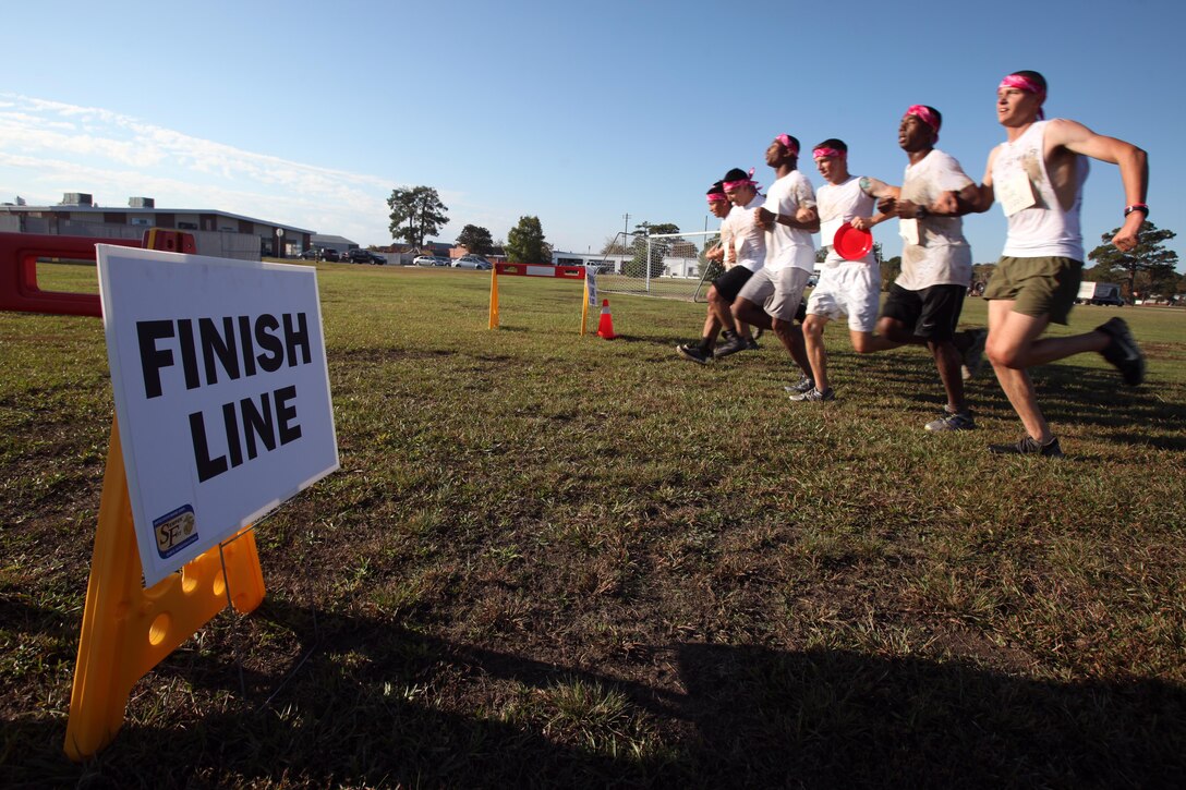 A team of service members link arms as they run toward the finish line during the annual Marine Special Operations Command All-Terrain Competition at Marine Corps Air Station Cherry Point, N.C., Oct. 30, 2015. Eleven teams of Marines and Sailors from the air station competed in the more than seven-mile competition. The first place winners were the Marine Aviation Logistics Squadron 14 Honey Badgers. (U.S. Marine Corps Photo by /Released)