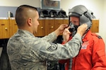 Air Force Staff Sgt. Luis Aguilar fits RAF Flight Lt. Kirsty Stewart with a helmet and oxygen mask in preparation for her F-16 orientation flight at the 162nd Fighter Wing at Tucson International Airport, Oct. 21, 2011. Stewart, a member of the United Kingdom's Red Arrows aerial demonstration team, was able to fly in the backseat of a Fighting Falcon with the international F-16 training wing.