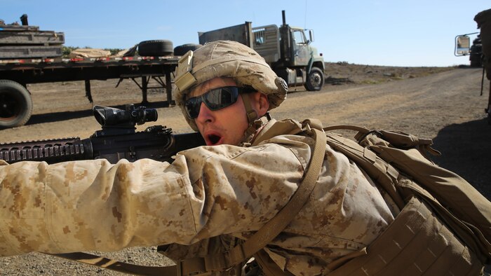 An infantryman with Assault Amphibian Vehicle Platoon, Company E, Battalion Landing Team 2/1, the ground combat element for the Boxer Amphibious Ready Group and 13th Marine Expeditionary Unit, fires from behind cover as an Assault Amphibian Vehicle moves into position to provide supporting fire during amphibious assault training as part of Composite Training Unit Exercise, Oct. 23, 2015. COMPTUEX provides the MEU ARG the opportunity to integrate naval training while also allowing focused, mission-specific training and evaluation for the Navy-Marine Corps team. 