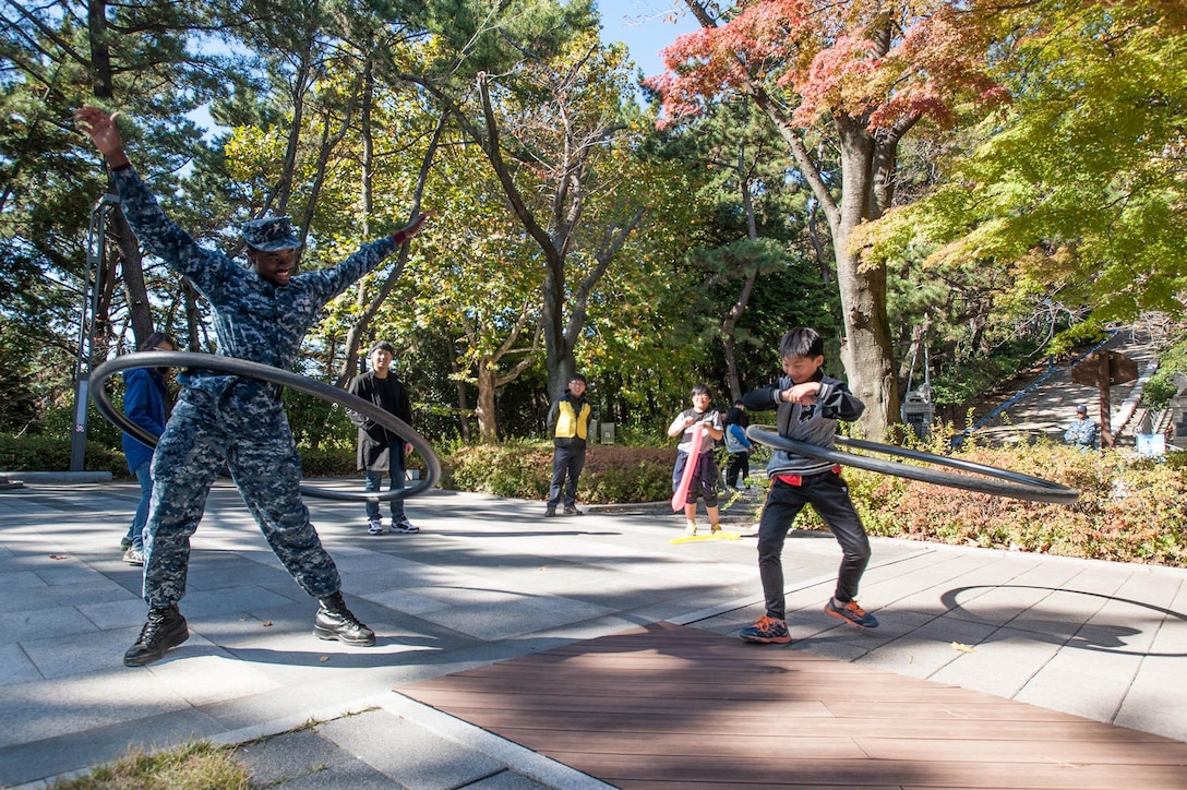 U.S. Navy Petty Officer 3rd Class Ransford Bulley hula-hoops with a child from Jinhae Hope Children Home during a community-relations event in Changwon, South Korea, Oct. 31, 2015. Bulley is an aviation boatswain’s mate with the USS Ronald Reagan, which is moored in Busan, South Korea, for a goodwill port visit. U.S. Navy photo by Petty Officer 3rd Class Nathan Burke