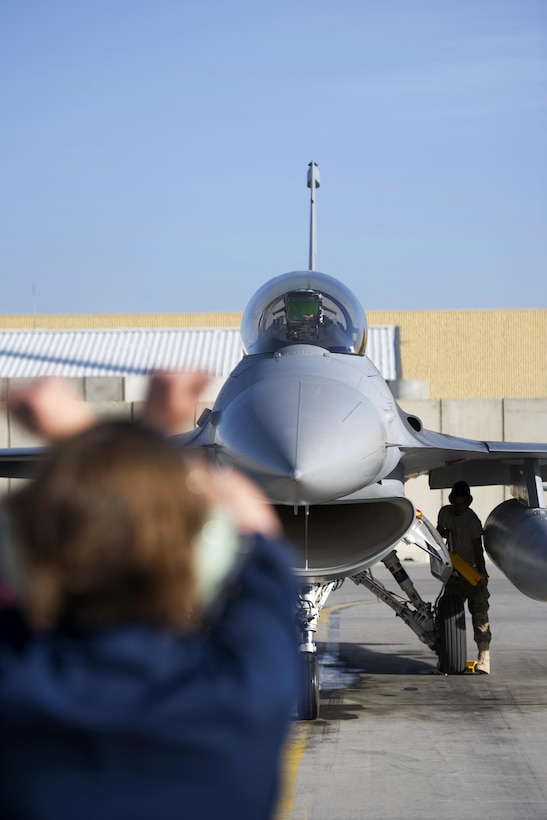 U.S. Air Force Staff Sgt. Eve Dorshorst guides an F-16 Fighting Falcon aircraft piloted by Maj. Vincent O'Connor to a spot on the ramp at Bagram Airfield, Afghanistan, Oct. 30, 2015. Dorshorst is a crew chief assigned to the 455th Expeditionary Aircraft Maintenance Squadron and O'Connor is a pilot assigned to the 555th Expeditionary Fighter Squadron. U.S. Air Force photo by Tech. Sgt. Robert Cloys