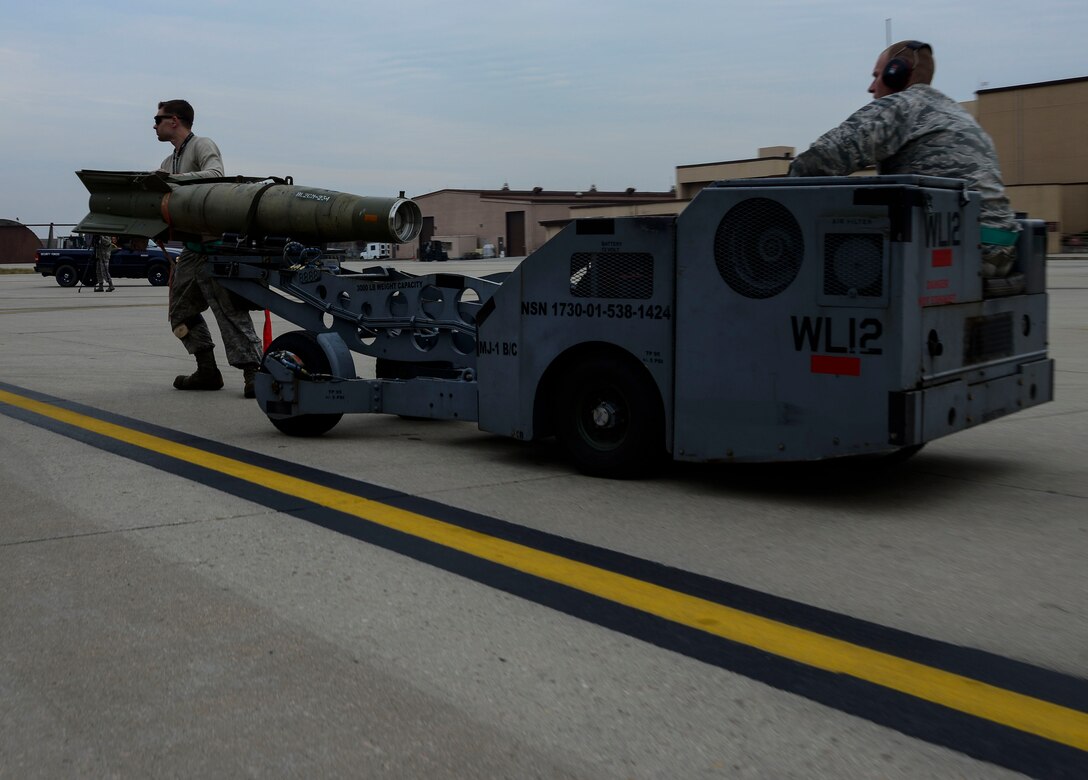 Staff Sgt. Christopher Uecker and Senior Airman Nathan Smith, 25th Aircraft Maintenance Unit weapons load crew team members, drive a guided bomb unit to be loaded onto an A-10 Thunderbolt II during the Vigilant Ace 16 exercise on Osan Air Base, Republic of Korea, Nov. 1, 2015. The weapons section of the 25th AMU is responsible for the maintenance and loading of various missiles, pylons, and other armament systems onto the A-10 fleet. (U.S. Air Force photo/Senior Airman Kristin High)