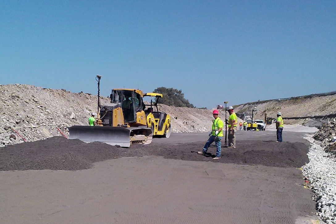 Contractors working on the new forebay wall at the Lockport Lock and Dam Upper Pool project use a bulldozer to spread a mixture of cement, water and crushed rock used in creating roller-compacted concrete (RCC). In total, the wall will contain approximately 80,000 cubic yards of RCC and will take nearly 4,000 off-road dump trucks to place the material.