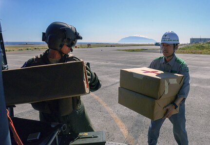 YOKOTA AIR BASE, Japan (Oct. 28, 2015) -  Staff Sgt. Christopher Rector (left), 459th Airlift Squadron special missions aviator, delivers simulated medical supplies to personnel at Miakejima Airport at Miakejima Island.  The United States military performs disaster relief exercises with the Metropolitan Government about twice a year, demonstrating readiness and supporting bilateral operations. 