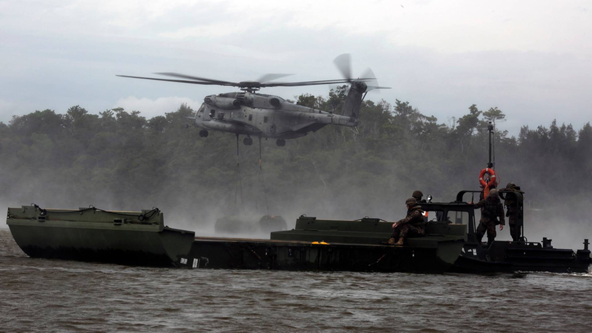 Marines move a component of a 15-bay Improved Ribbon Bridge as a CH-53E Super Stallion helicopter inserts bridge components into the water in the Central Training Area, Okinawa, Japan, during Blue Chromite 2016, Nov. 2, 2015. This was the first time that Improved Ribbon Bridges, flat modular-floating platforms that bridge wet gaps, were inserted by air on Okinawa. Blue Chromite is a large-scale amphibious exercise that draws primarily from III Marine Expeditionary Force’s training resources on Okinawa. The location of the training allows participating units to maintain a forward-deployed posture and eliminates the cost of traveling to train. The Marines are with 9th Engineer Support Battalion, 3rd Marine Logistics Group, III Marine Expeditionary Force. The Super Stallion is with Marine Heavy Helicopter Squadron 462. (U.S. Marine Corps photo by Cpl. Drew Tech/Released)