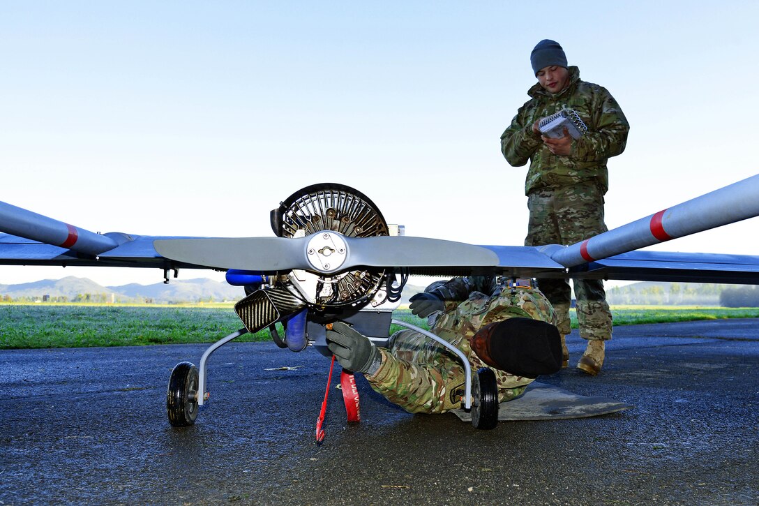 U.S. Army Sgt. Desmond Herring, lying down, conducts preflight checks on an RQ7B unmanned aircraft system during Exercise Rock Proof V at Aeroclub Postonja, Slovenia, Oct. 20, 2015. Herring is a U.S. paratrooper assigned to Company D, 54th Brigade Engineer Battalion, 173rd Airborne Brigade. The training exercise, which occurs between U.S. and Slovenian forces, focuses on small-unit tactics and building interoperability between allied forces. U.S. Army photo by Paolo Bovo