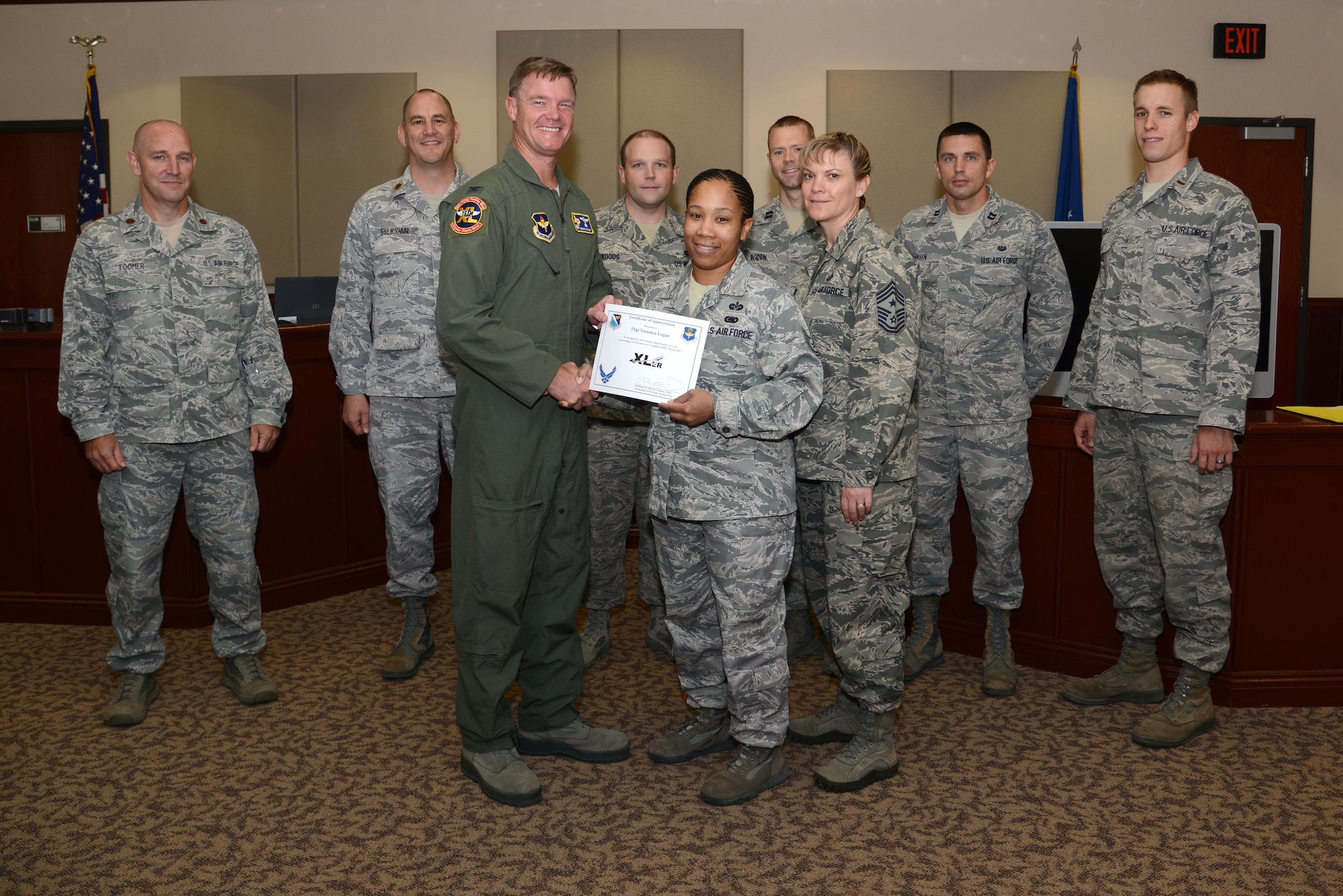 Technical Sgt. Veronica Logan, center, 47th Flying Training Wing judge advocate NCO in charge, poses with Col. Thomas Shank, 47th Flying Training Wing commander, Chief Master Sgt. Teresa Clapper, 47th Flying Training Wing command chief, after accepting the “XLer of the Week” award, here, Oct. 28, 2015. The “XLer” is a weekly award chosen by wing leadership and is presented to those who consistently make outstanding contributions to their unit and Laughlin. (U.S. Air Force photo by Airman 1st Class Ariel D. Partlow) (Released)