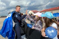 Jenna Koch(center),gives a high five to Cadet 1st Class Garrett Nobley, U.S. Air Force Academy Wings of Blue team member, during the 2015 Joint Base San Antonio Air Show and Open House Nov. 1, 2015 at JBSA-Randolph, Texas. Air shows allow the Air Force to display the capabilities of our aircraft to the American taxpayer through aerial demonstrations and static displays and allowing attendees to get up close and personal to see some of the equipment and aircraft used by the U.S. military today. (U.S. Air Force photo by Johnny Saldivar) 

