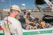 Troy Creason, left, looks on while his daughters Connal, right, and Gloria sit in a cockpit during the 2015 Joint Base San Antonio Air Show and Open House Nov. 1, 2015 at JBSA-Randolph, Texas. Air shows allow the Air Force to display the capabilities of our aircraft to the American taxpayer through aerial demonstrations and static displays and allowing attendees to get up close and personal to see some of the equipment and aircraft used by the U.S. military today. (U.S. Air Force photo by Johnny Saldivar) 
