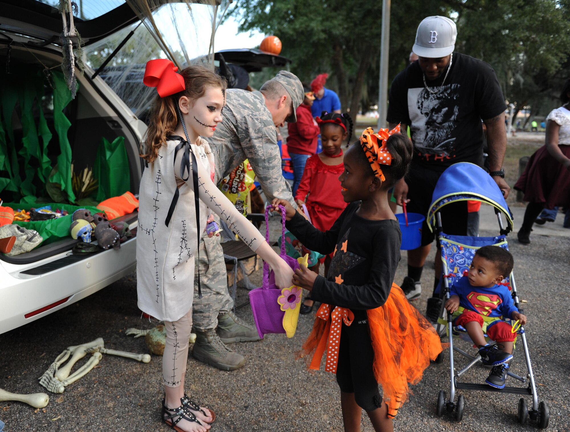 Shannon Jones, daughter of Senior Master Sgt. Shawn Jones, 334th Training Squadron aviation resource management superintendent, passes pieces of candy to Lola Morgan, daughter of Staff Sgt. David Morgan, 81st Logistics Readiness Squadron traffic manager, as they participate in a “Trunk or Treat” during Ghouls in the Park at marina park, Oct. 30, 2015, Keesler Air Force Base, Miss. Ghouls in the Park also featured games with prizes and a haunted house.  (U.S. Air Force photo by Kemberly Groue)