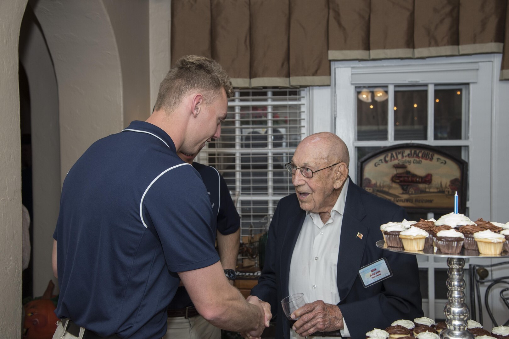 Retired Lt. Col. Richard Cole, Doolittle Raider, speaks with a member of the U.S. Air Force Wings of Blue Parachute Team during his 100th birthday celebration Oct. 30, 2015, at Joint Base San Antonio-Randolph. The reception afforded General Roberson and attendees an opportunity to interact with an individual who represents a linkage to Air Force heritage.  The event also bridged the past and present, and offered Airmen a chance to interact with a living legend. (U.S. Air Force photo by Airman 1st Class Stormy Archer/Released)