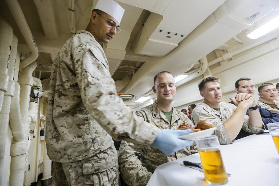 GULF OF ADEN (Oct. 29, 2015) U.S. Marine Staff Sgt. James Leach, left, serves Cpl. Andrew Goldhis meal for the October birthday dinner aboard the USS Anchorage (LPD 23). Leach is a platoon sergeant and Gold is machine gunner with Battalion Landing Team 3rd Battalion, 1st Marine Regiment, 15th Marine Expeditionary Unit. Marines and Sailors celebrate their birthdays for the month of October with a steak and lobster tail dinner served by their staff noncommissioned officers. The 15th MEU, embarked on the ships of the Essex Amphibious Ready Group, is deployed to maintain regional security in the U.S. 5th Fleet area of operations. (U.S. Marine Corps photo by Sgt. Jamean Berry/Released)