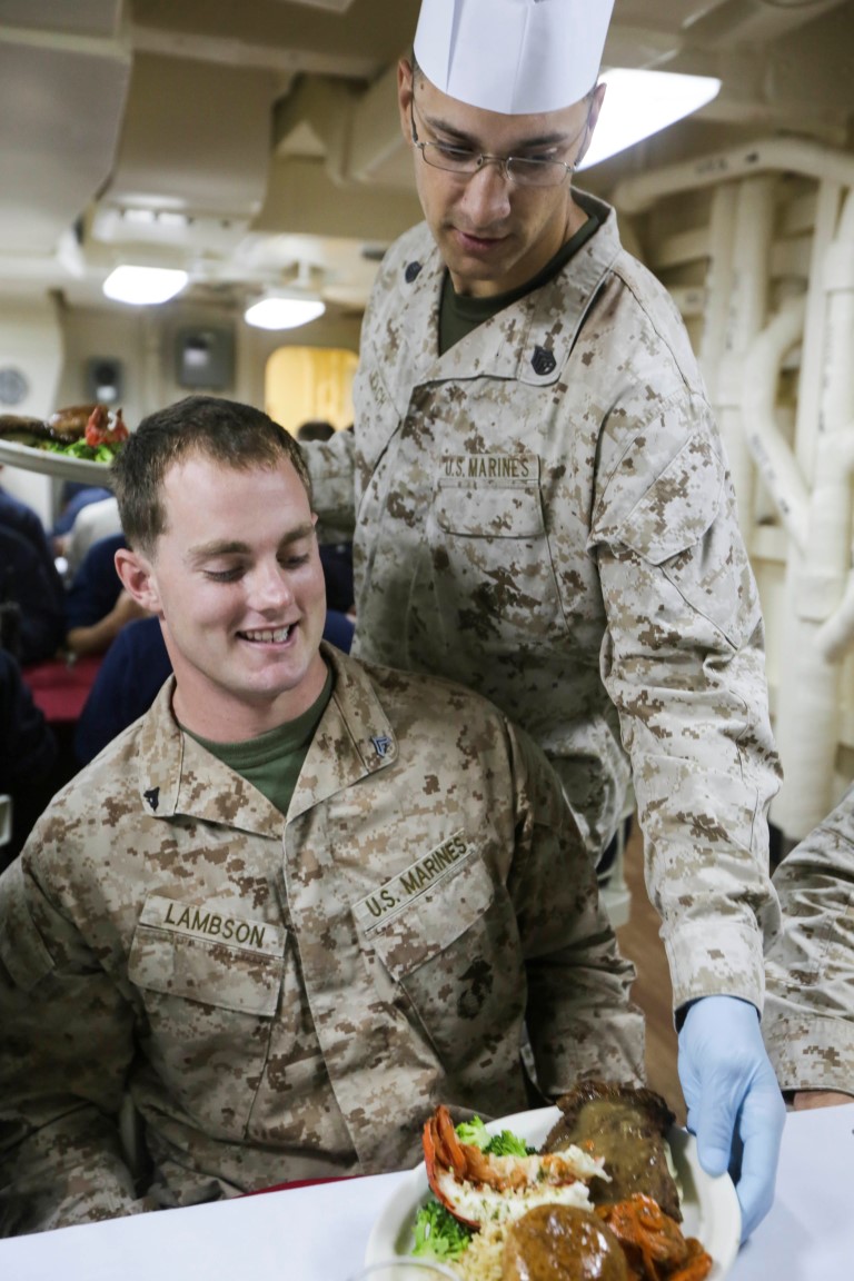 GULF OF ADEN (Oct. 29, 2015) U.S. Marine Staff Sgt. James Leach, right, serves Cpl. Cody Lambson his meal for the October birthday dinner aboard the USS Anchorage (LPD 23).  Leach is a platoon sergeant with Battalion Landing Team 3rd Battalion, 1st Marine Regiment, 15th Marine Expeditionary Unit, and Lambson is a scout with the 15th MEU’s Force Reconnaissance Detachment.  Marines and Sailors celebrate their birthdays for the month of October with a steak and lobster tail dinner served by their staff noncommissioned officers.  The 15th MEU, embarked on the ships of the Essex Amphibious Ready Group, is deployed to maintain regional security in the U.S. 5th Fleet area of operations.  (U.S. Marine Corps photo by Sgt. Jamean Berry/Released)