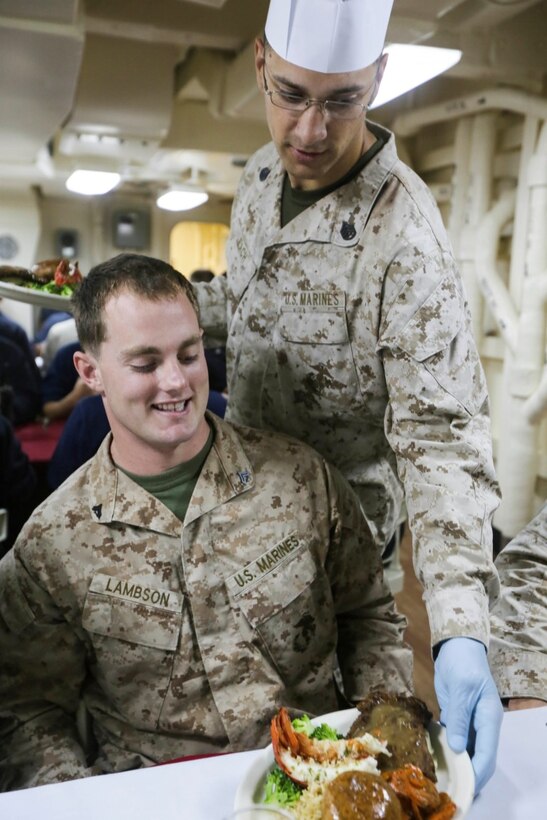 GULF OF ADEN (Oct. 29, 2015) U.S. Marine Staff Sgt. James Leach, right, serves Cpl. Cody Lambson his meal for the October birthday dinner aboard the USS Anchorage (LPD 23).  Leach is a platoon sergeant with Battalion Landing Team 3rd Battalion, 1st Marine Regiment, 15th Marine Expeditionary Unit, and Lambson is a scout with the 15th MEU’s Force Reconnaissance Detachment.  Marines and Sailors celebrate their birthdays for the month of October with a steak and lobster tail dinner served by their staff noncommissioned officers.  The 15th MEU, embarked on the ships of the Essex Amphibious Ready Group, is deployed to maintain regional security in the U.S. 5th Fleet area of operations.  (U.S. Marine Corps photo by Sgt. Jamean Berry/Released)
