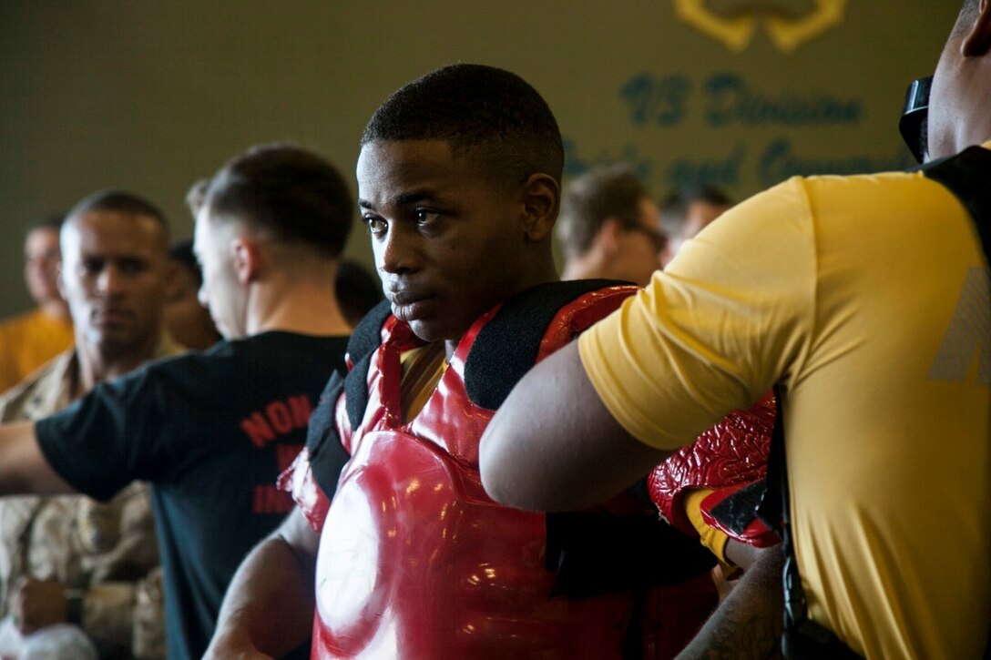 INDIAN OCEAN (Oct. 31, 2015) U.S. Marines with the 15th Marine Expeditionary Unit and Navy Sailors with the Essex Amphibious Ready Group prepare their gear prior to being sprayed with oleoresin capsicum in the hangar bay of the amphibious assault ship USS Essex (LHD 2). The Marines and Sailors are going through a non-lethal weapons course to learn different techniques they might need while on watch-stander duty. (U.S. Marine Corps photo by Cpl. Elize McKelvey/Released)