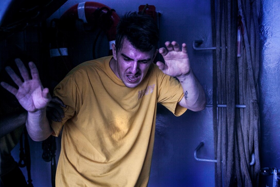 INDIAN OCEAN (Oct. 31, 2015) A U.S. Sailor with the Essex Amphibious Ready Group turns a bright corner after being sprayed with oleoresin capsicum in the hangar bay of the amphibious assault ship USS Essex (LHD 2). The Marines and Sailors are going through a non-lethal weapons course to learn different techniques they might need while on watch-stander duty. (U.S. Marine Corps photo by Cpl. Elize McKelvey/Released)