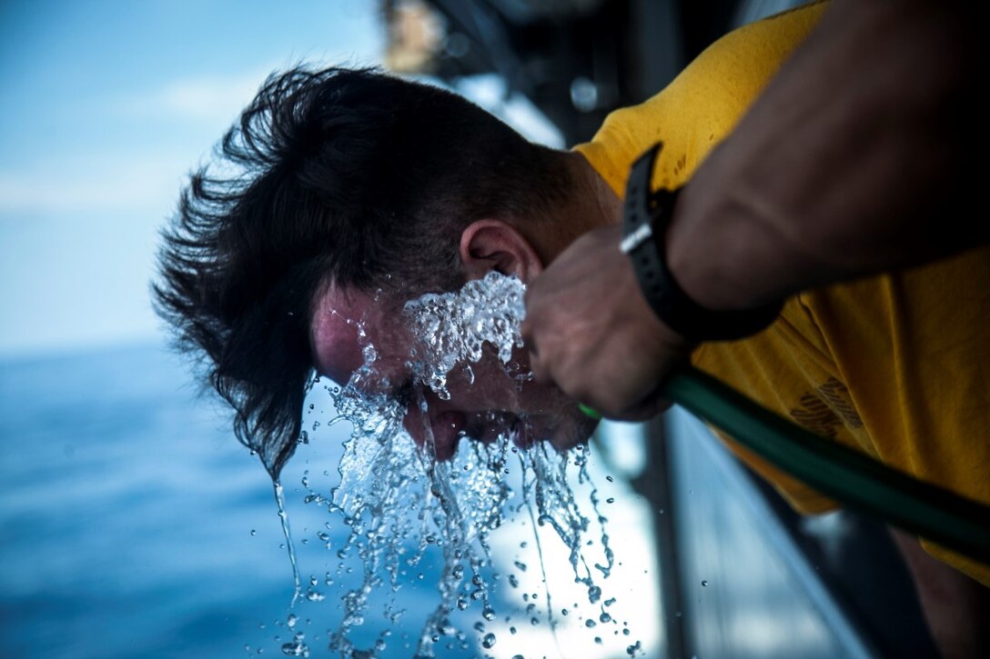 INDIAN OCEAN (Oct. 31, 2015) A U.S. Sailor with the Essex Amphibious Ready Group washes his face after being sprayed with oleoresin capsicum in the hangar bay of the amphibious assault ship USS Essex (LHD 2). The Marines and Sailors are going through a non-lethal weapons course to learn different techniques they might need while on watch-stander duty. (U.S. Marine Corps photo by Cpl. Elize McKelvey/Released)