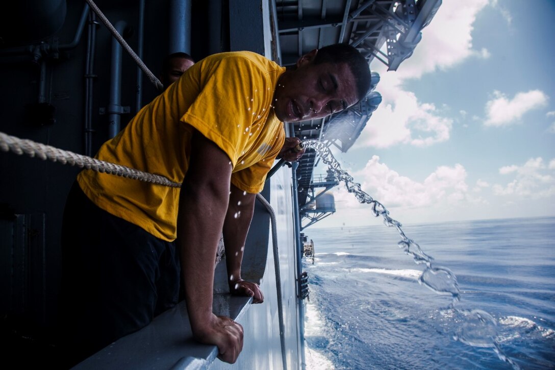 INDIAN OCEAN (Oct. 31, 2015) A U.S. Sailor with the Essex Amphibious Ready Group washes his face after being sprayed with oleoresin capsicum in the hangar bay of the amphibious assault ship USS Essex (LHD 2). The Marines and Sailors are going through a non-lethal weapons course to learn different techniques they might need while on watch-stander duty. (U.S. Marine Corps photo by Cpl. Elize McKelvey/Released)