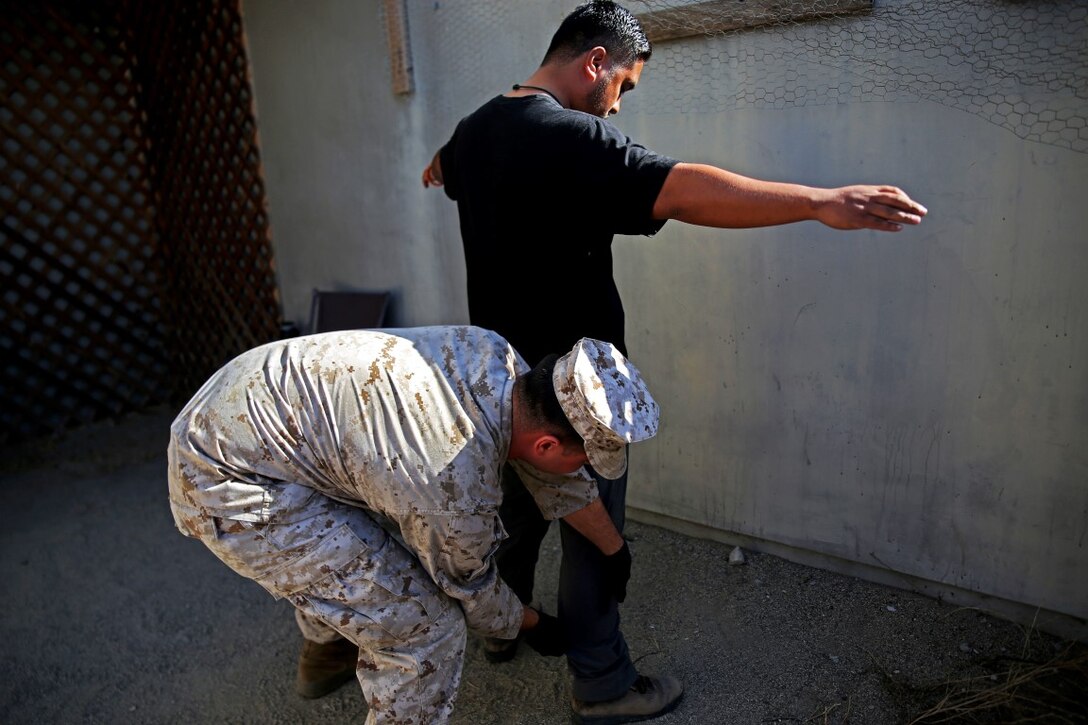 Lance Cpl. Anthony Doyle, a warehouse clerk with Headquarters and Service Company, 1st Battalion, 5th Marine Regiment, 1st Marine Division, searches a role-playing suspect after searching his house during searchers and site exploitation training aboard Marine Corps Base Camp Pendleton, Calif., Oct. 29, 2015. Instructors with the Marines Corps Engineer Society taught the Marines the skills they need to locate and collect evidence on munitions or against suspected individuals in a realistic training environment.