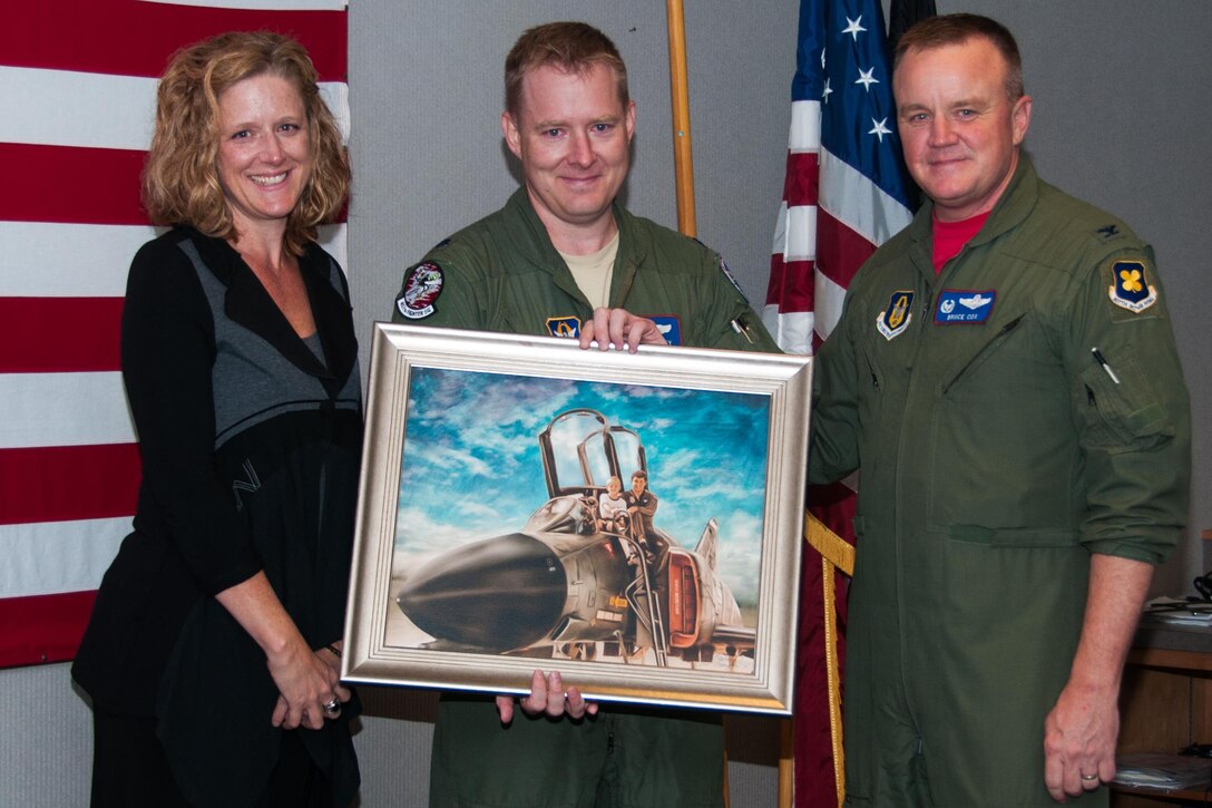 U.S. Air Force Col. Bruce Cox (right), commander of the 307th Bomb Wing, Barksdale Air Force Base, La., presents Lt. Col. Brian Bailey (center) and his sister Beth (left) with a picture in memory of their father, Maj. John “Trapper” Bailey on behalf of the 457th Fighter Squadron “Spads,” at Naval Air Station, Joint Reserve Base Fort Worth, Texas, on Oct. 23, 2015. John Bailey was an F-4 pilot assigned to the 457th Fighter Squadron when he died in an aircraft crash near Carswell AFB, Texas in 1987.  The “Spads” have a memorial of John Bailey in their building. (U.S. Air Force photo by Master Sgt. Laura Siebert/Released)