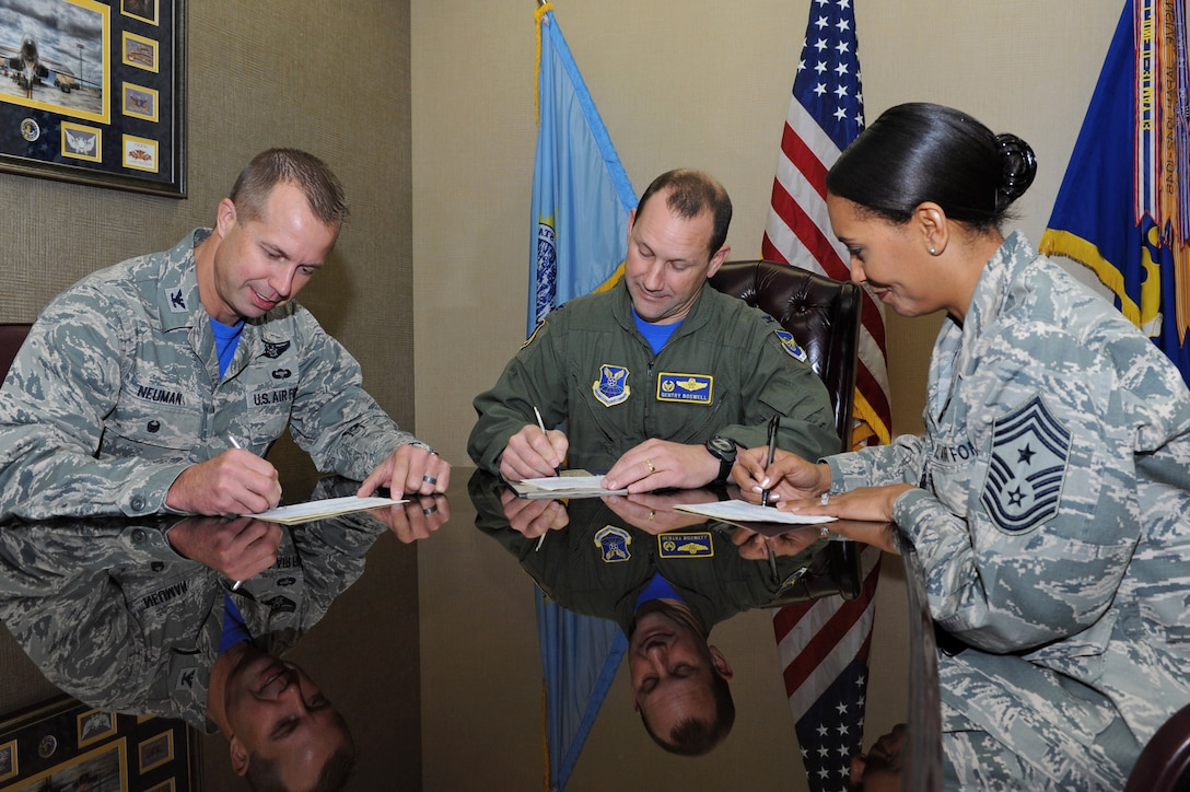 Col. Gentry Boswell, 28th Bomb Wing commander, middle, Col. Ty Neuman, 28th BW vice commander, left, and Chief Master Sgt. Sonia Lee, 28th BW command chief, right, sign Combined Federal Campaign donation forms at Ellsworth Air Force Base, S.D., Oct. 30, 2015. Ellsworth Airmen have contributed more than $60,000 this year, helping local and national charities. (U.S. Air Force photo by Senior Airman Hailey Staker/Released) 