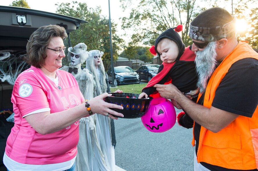 Aleena, daughter of U.S. Air Force Staff Sgt. Chris Safis, 71st Aircraft Maintenance Unit, collects candy from Margaret Lipp, youth center trainer, during Trunk or Treat Oct. 31, 2015, at Moody Air Force Base, Ga. This year was Aleena’s first time participating in Moody’s trick or treat festivities. (U.S. Air Force photo by Senior Airman Ceaira Tinsley/Released)