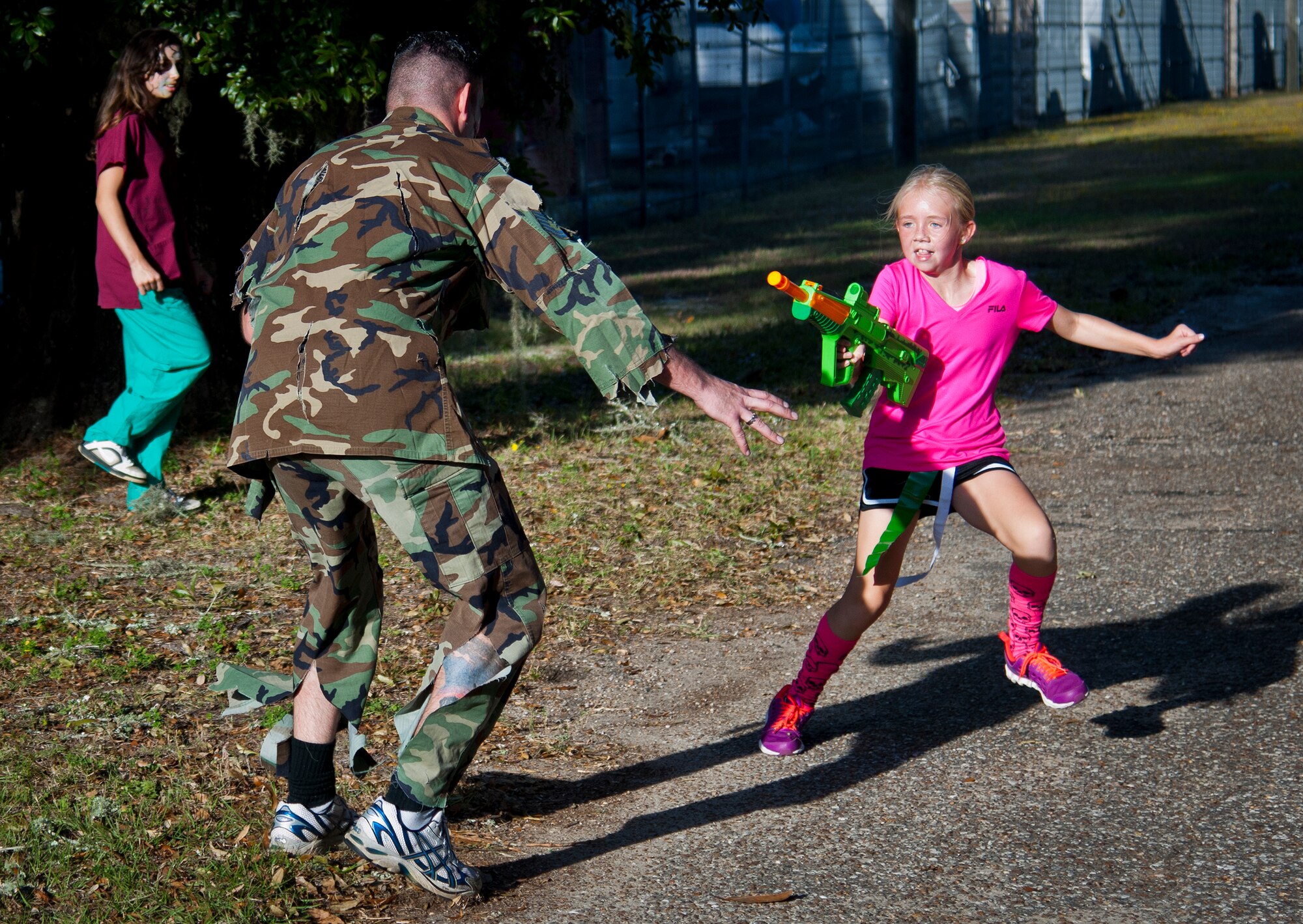 A participant aims for the head of her zombie attacker during the annual Zombie Stomp run Oct. 30 at Eglin Air Force Base, Fla.  More than 150 turned out to duck, dodge and outrun zombie hordes throughout the 5k run.  (U.S. Air Force photo/Samuel King Jr.)