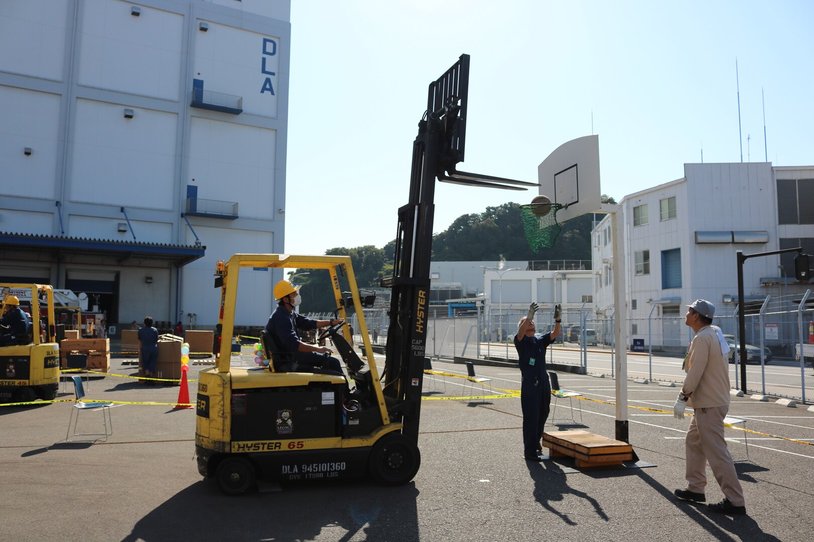 Participants use a forklift to shoot a basketball through a hoop during DLA Distribution Yokosuka's annual Forklift Rodeo.