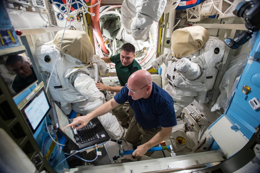 Astronauts Scott Kelly, front, and Kjell Lindgren, a 1995 Air Force Academy graduate, prepare their extravehicular mobility unit spacesuits and tools in the Quest airlock of the International Space Station. Kelly and Lindgren will use the spacesuits for a spacewalk outside the station Nov. 6, 2015. (NASA courtesy photo)
