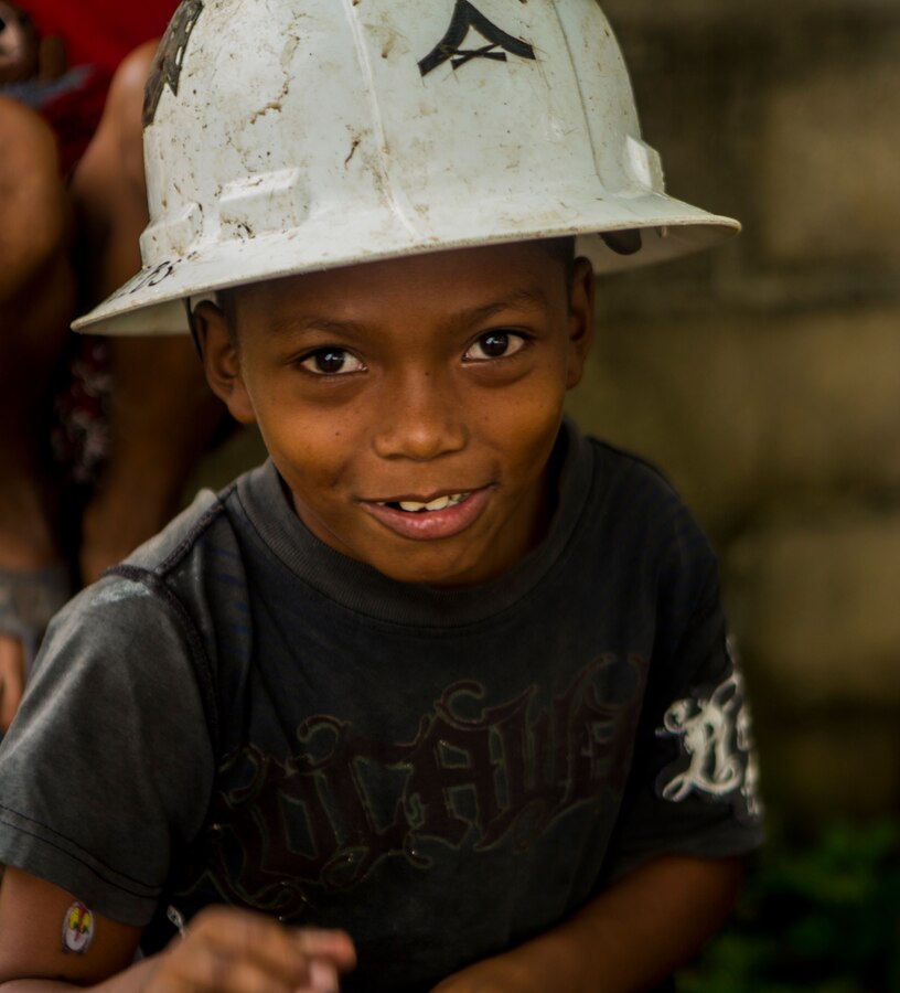 A young boy wears a hard hat while U.S. Marines with Special Purpose Marine Air-Ground Task Force-Southern Command continue construction on a new classroom at Victor Hugo School in Puerto Lempira, Honduras, Sept. 24, 2015. SPMAGTF-SC is a temporary deployment of Marines and Sailors throughout Honduras, El Salvador, Guatemala, and Belize with a focus on building and maintaining partnership capacity with each country through shared values, challenges, and responsibility. (U.S. Marine Corps Photo by Cpl. Katelyn Hunter/Released).