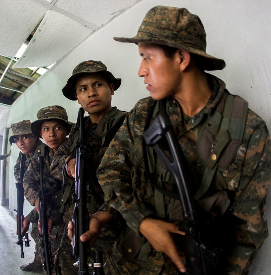 Marines and soldiers with Brigada de Infanteria Marina line up outside of a door before clearing a room during the urban operations training portion of an Urban Combat Course led by U.S. Marines with Security Cooperation Team-Guatemala, Special Purpose Marine Air-Ground Task Force Southern Command in Puerto Barrios, Guatemala, Sept. 25, 2015. SPMAGTF-SC is a temporary deployment of Marines and Sailors throughout Honduras, El Salvador, Guatemala, and Belize with a focus on building and maintaining partnership capacity with each country through shared values, challenges, and responsibilities. (U.S. Marine Corps photo by Lance Cpl. Abraham Lopez/Released)