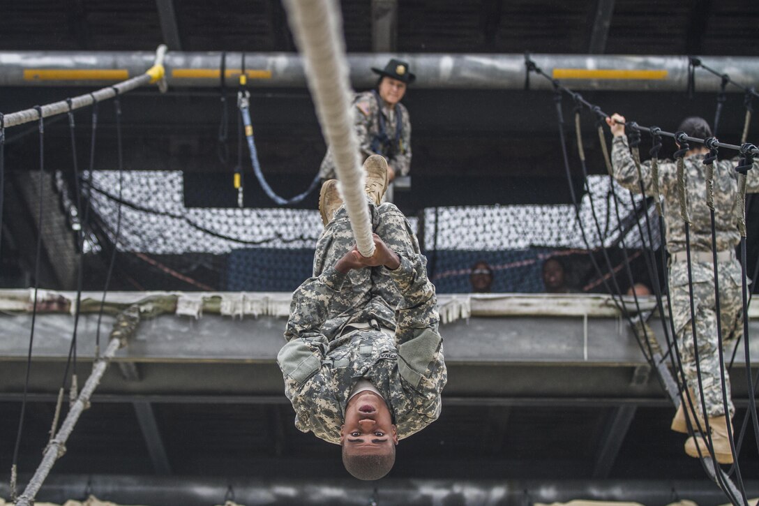 After losing his balance on a rope bridge obstacle, a soldier in Basic Combat Training attempts to shimmy across to the other side while his drill sergeant watches on Fort Jackson, S.C., Oct. 28, 2015. The soldier is assigned to Company E, 2nd Battalion, 39th Infantry Regiment. U.S. Army photo by Sgt. 1st Class Brian Hamilton
