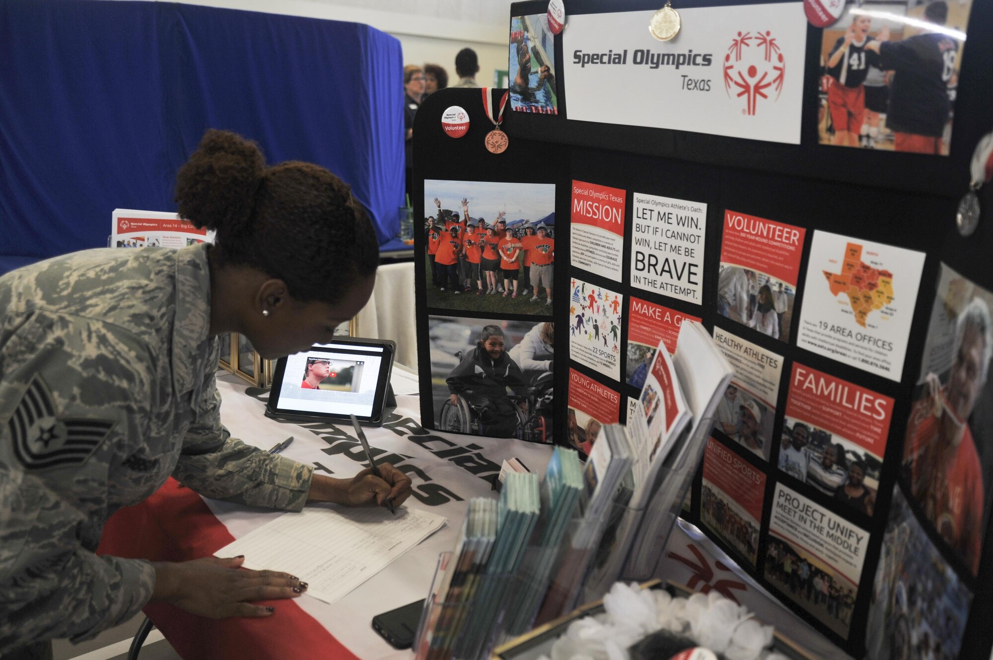 U.S. Air Force Tech. Sgt. Curtrell L. Gibson, 17th Force Support Squadron Airman Leadership School instructor, signs her name on a volunteer sheet at the Special Olympics booth during the Volunteer Fair at the Carswell Field House on Goodfellow Air Force Base, Texas, Oct. 28, 2015. Volunteers can serve as coaches, officials, committee members, competition assistants and more. (U.S. Air Force photo by Airman Chase Sousa/Released)