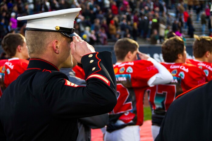 Sgt. Matthew Boulis, recruiter with Recruiting Sub Station Grand Rapids North, Mich., and a football player from Lowell High School, salute the flag during the National Anthem  before the start of the Great American Rivalry Series game between Lowell and East Grand Rapids high schools, Oct. 16, 2015. The Great American Rivalry Series games allowed Marines, football players and the school’s student body to interact over a relatable common ground topic: competition. 