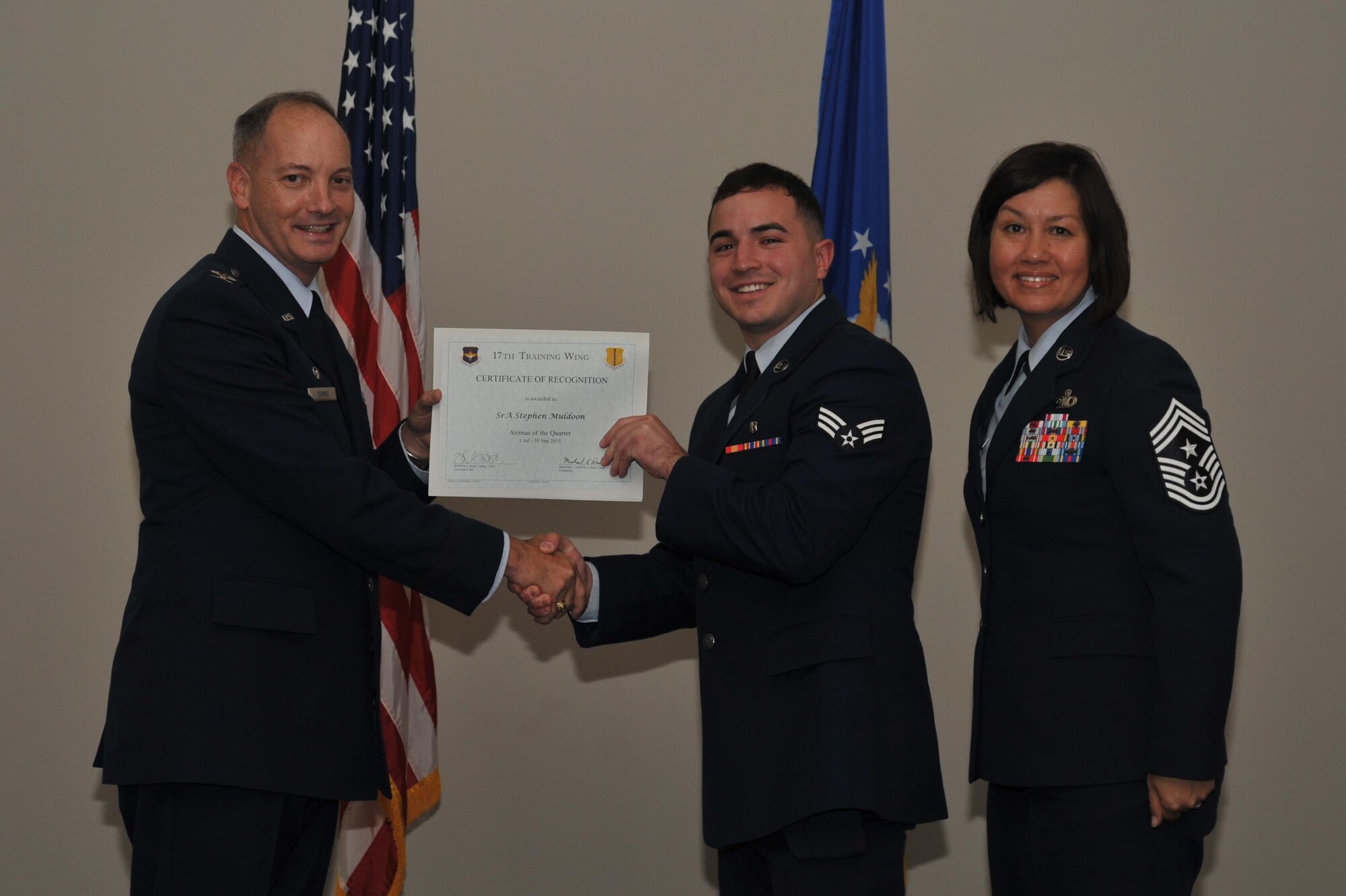 U.S. Air Force Col. Michael L. Downs, 17th Training Wing Commander, and Chief Master Sgt. JoAnne S. Bass, 17th TRW Command Chief, present the Airman of the Quarter award to Senior Airman Stephen Muldoon, 17th Medical Group, during the wing quarterly awards ceremony at the Event Center on Goodfellow Air Force Base, Texas, Oct. 30, 2015. (U.S. Air Force photo by Airman Chase Sousa/Released)