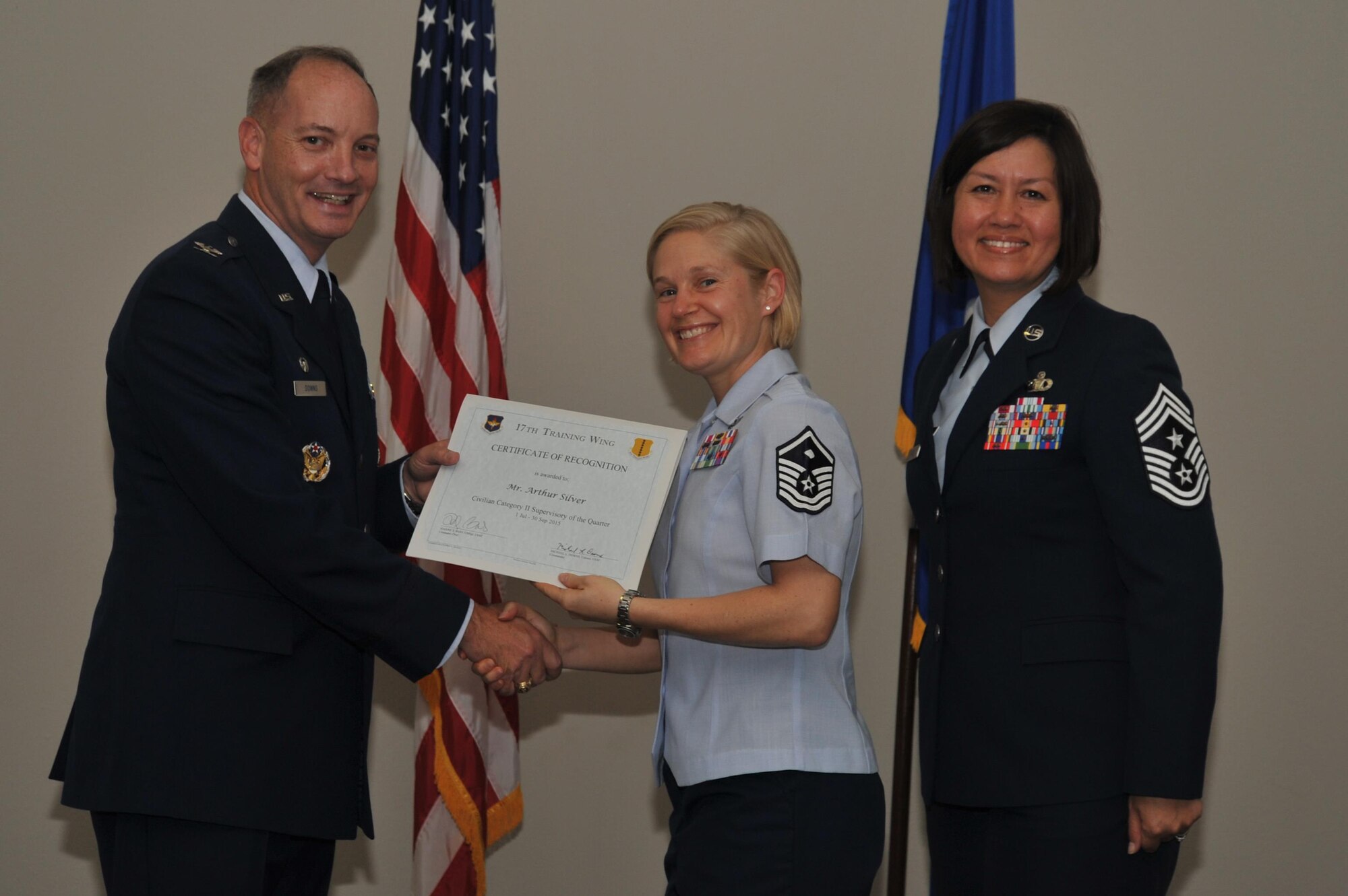 U.S. Air Force Col. Michael L. Downs, 17th Training Wing Commander, and Chief Master Sgt. JoAnne S. Bass, 17th TRW Command Chief, present the Civilian Category II Supervisory of the Quarter Award to Master Sgt. Brenda J. Dodson, 17th Force Support Squadron first sargent., on behalf of Arthur Silver, 17th Mission Support Group, during the wing quarterly awards ceremony at the Event Center on Goodfellow Air Force Base, Texas, Oct. 30, 2015. (U.S. Air Force photo by Airman Chase Sousa/Released)