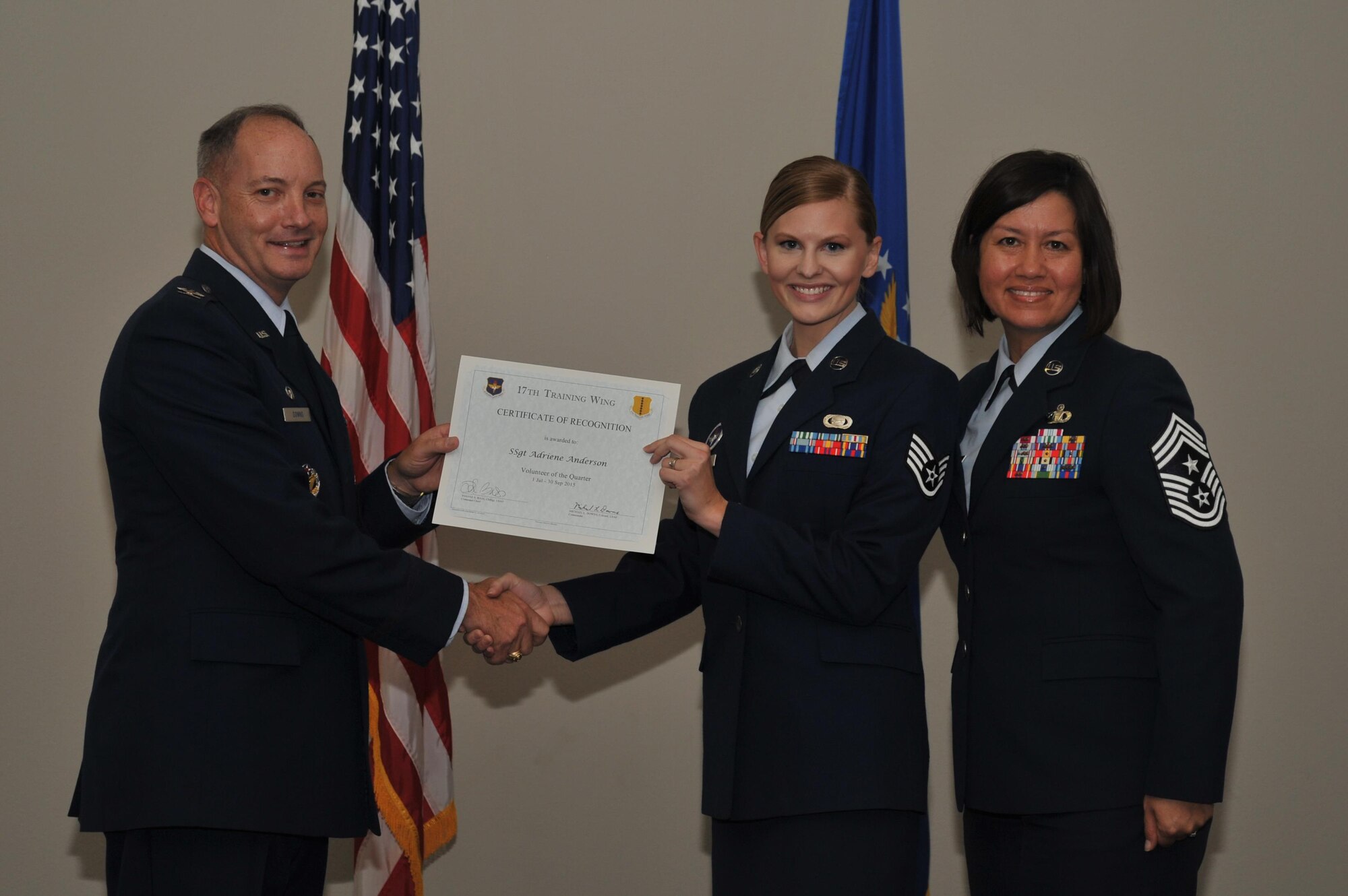 U.S. Air Force Col. Michael L. Downs, 17th Training Wing Commander, and Chief Master Sgt. JoAnne S. Bass, 17th TRW Command Chief, present the Volunteer of the Quarter Award to Staff Sgt. Adriene Anderson, 17th Training Group, during the wing quarterly awards ceremony at the Event Center on Goodfellow Air Force Base, Texas, Oct. 30, 2015. (U.S. Air Force photo by Airman Chase Sousa/Released)