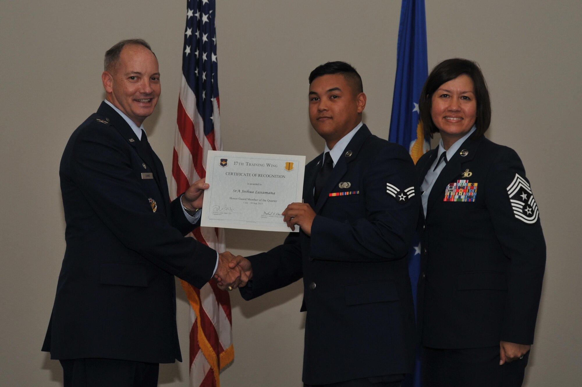 U.S. Air Force Col. Michael L. Downs, 17th Training Wing Commander, and Chief Master Sgt. JoAnne S. Bass, 17th TRW Command Chief, present the Honor Guard Member of the Quarter Award to Senior Airman Joshua Laxamana, 17th Communication Squadron, during the wing quarterly awards ceremony at the Event Center on Goodfellow Air Force Base, Texas, Oct. 30, 2015. (U.S. Air Force photo by Airman Chase Sousa/Released)
