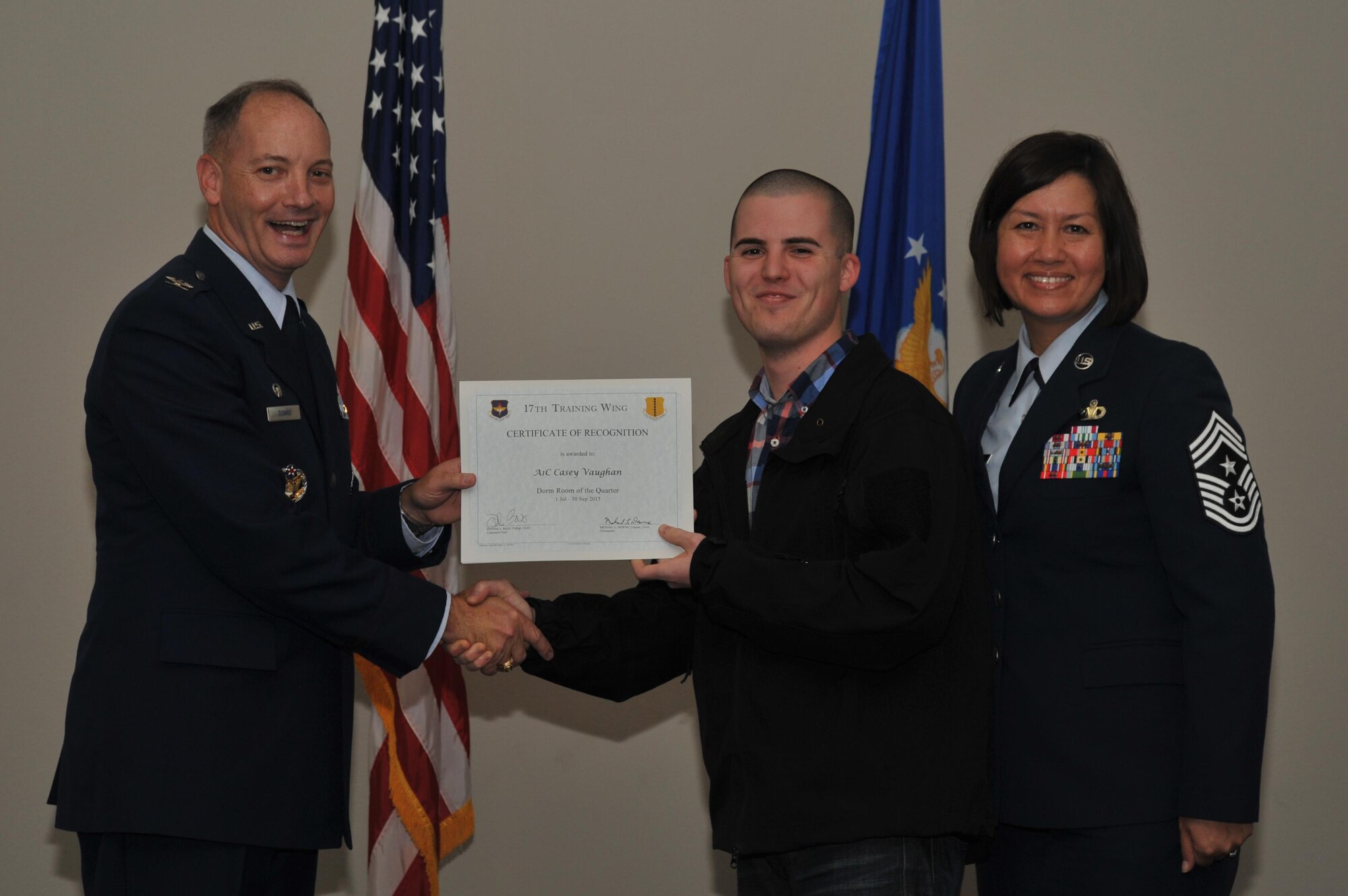 U.S Air Force Col. Michael L. Downs, 17th Training Wing Commander, and Chief Master Sgt. JoAnne S. Bass, 17th TRW Command Chief, present the Dorm Room of the Quarter Award to Airman 1st Class Casey Vaughan, 17th Medical Group, during the wing quarterly awards ceremony at the Event Center on Goodfellow Air Force Base, Texas, Oct. 30, 2015. (U.S. Air Force photo by Airman Chase Sousa/Released)