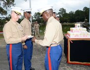 Installation officials, Marines, civilian-Marines and personnel from Marine Corps Logistics Base Albany’s tenant commands gather for a morning of pageants, Corps' history and cake-cutting in celebration of the Marine Corps’ 240th birthday, here, Nov. 3. The annual commemoration, which was held at the Amphitheater in Boyett Park/Covella Pond, featured Marines dressed in an array of uniforms and carrying weapons from specific eras, past to present, during a narration of the Marine Corps’ 240-year history. Col. James C. Carroll III, commanding officer, MCLB Albany, cut the traditional birthday cake and presented a slice to the installation’s oldest serving Marine present at the ceremony, Lt. Col. Walter Wilkie, who passed it to the youngest Marine present, Lance Cpl. Alandre Brown. The passing of the cake from the oldest to the youngest Marine symbolizes the passing of history and traditions to the next generation.
