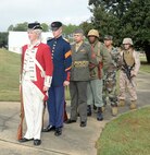 Installation officials, Marines, civilian-Marines and personnel from Marine Corps Logistics Base Albany’s tenant commands gather for a morning of pageants, Corps' history and cake-cutting in celebration of the Marine Corps’ 240th birthday, here, Nov. 3. The annual commemoration, which was held at the Amphitheater in Boyett Park/Covella Pond, featured Marines dressed in an array of uniforms and carrying weapons from specific eras, past to present, during a narration of the Marine Corps’ 240-year history. Col. James C. Carroll III, commanding officer, MCLB Albany, cut the traditional birthday cake and presented a slice to the installation’s oldest serving Marine present at the ceremony, Lt. Col. Walter Wilkie, who passed it to the youngest Marine present, Lance Cpl. Alandre Brown. The passing of the cake from the oldest to the youngest Marine symbolizes the passing of history and traditions to the next generation.