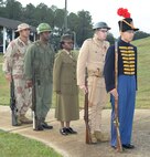 Installation officials, Marines, civilian-Marines and personnel from Marine Corps Logistics Base Albany’s tenant commands gather for a morning of pageants, Corps' history and cake-cutting in celebration of the Marine Corps’ 240th birthday, here, Nov. 3. The annual commemoration, which was held at the Amphitheater in Boyett Park/Covella Pond, featured Marines dressed in an array of uniforms and carrying weapons from specific eras, past to present, during a narration of the Marine Corps’ 240-year history. Col. James C. Carroll III, commanding officer, MCLB Albany, cut the traditional birthday cake and presented a slice to the installation’s oldest serving Marine present at the ceremony, Lt. Col. Walter Wilkie, who passed it to the youngest Marine present, Lance Cpl. Alandre Brown. The passing of the cake from the oldest to the youngest Marine symbolizes the passing of history and traditions to the next generation.