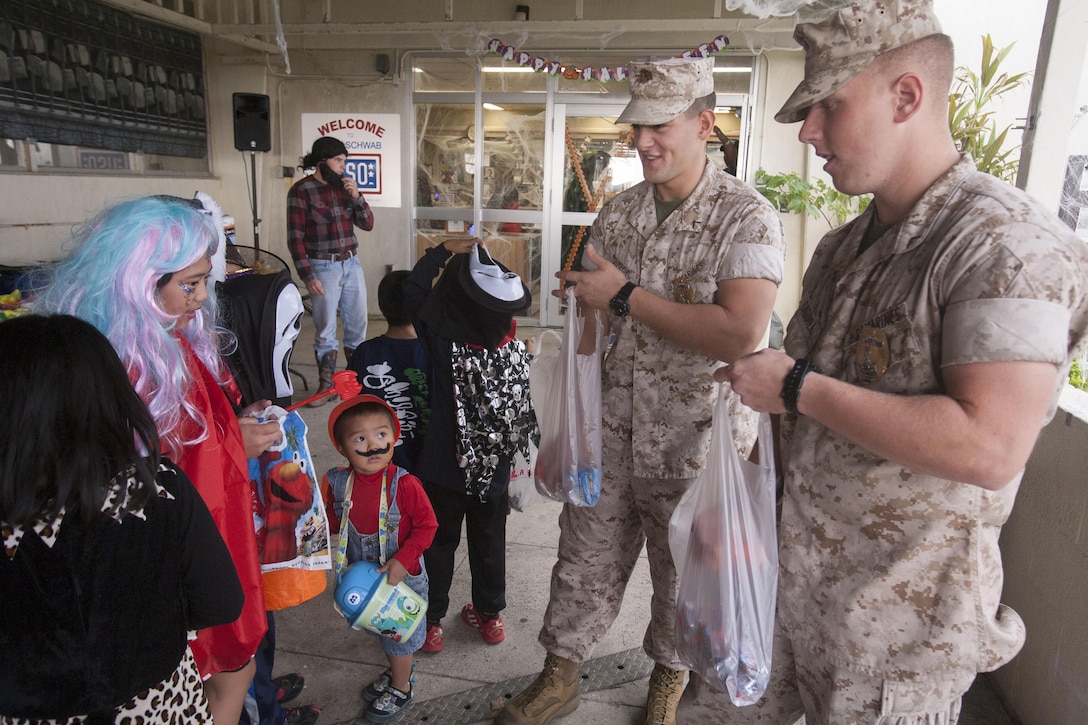 Private First Class Matthew Caudill, right, and Pfc. Christopher Dimech pass out candy to children from the Henoko community at the Trunk-or-Treat event on Camp Schwab, Okinawa, Japan, on Oct. 31. This was the first year a Halloween event was held on base for the members of the Okinawa community. There was food, candy and face painting at the event. Caudill, from Nashville, Tennessee, and Dimech, from New York City, New York, are both military policemen with 3rd Law Enforcement Battalion, III Marine Expeditionary Force Headquarters Group, III MEF.