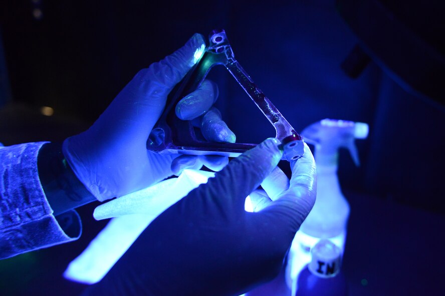 Senior Airman Cody Reynolds, 56th Equipment Maintenance Squadron nondestructive inspection apprentice, inspects A frames from an F-16 Fighting Falcon under a black light at Luke Air Force Base, Arizona, Oct. 30, 2015. The A frames were put through wet fluorescents and dipped inside penetrants prior to black light viewing. The penetrants cause a capillary action when there are cracks present in parts and become visible under black light viewing. (U.S. Air Force photo by Senior Airman James Hensley)   