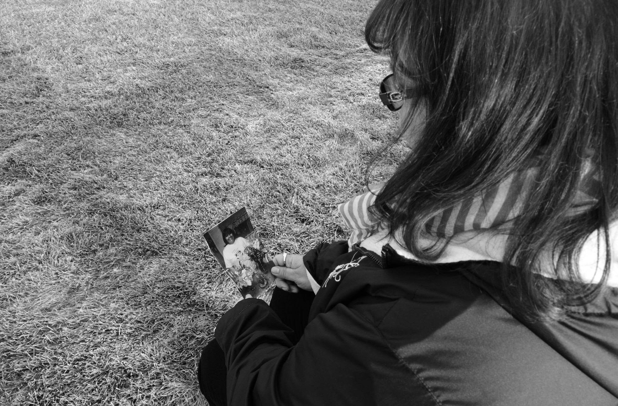 Cathy Fitzgerald, the financial and computer support assistant for the Air Force Office of Special Investigations detachment at Eielson Air Force Base, Alaska, looks over an older photo of herself during a break Oct. 26, 2015. Fitzgerald reflected on the photo from October 2009 that was taken during her final day of chemotherapy. Fitzgerald endured a long and difficult fight against breast cancer but came out a survivor. (U.S. Air Force photo by Airman 1st Class Cassandra Whitman/Released)