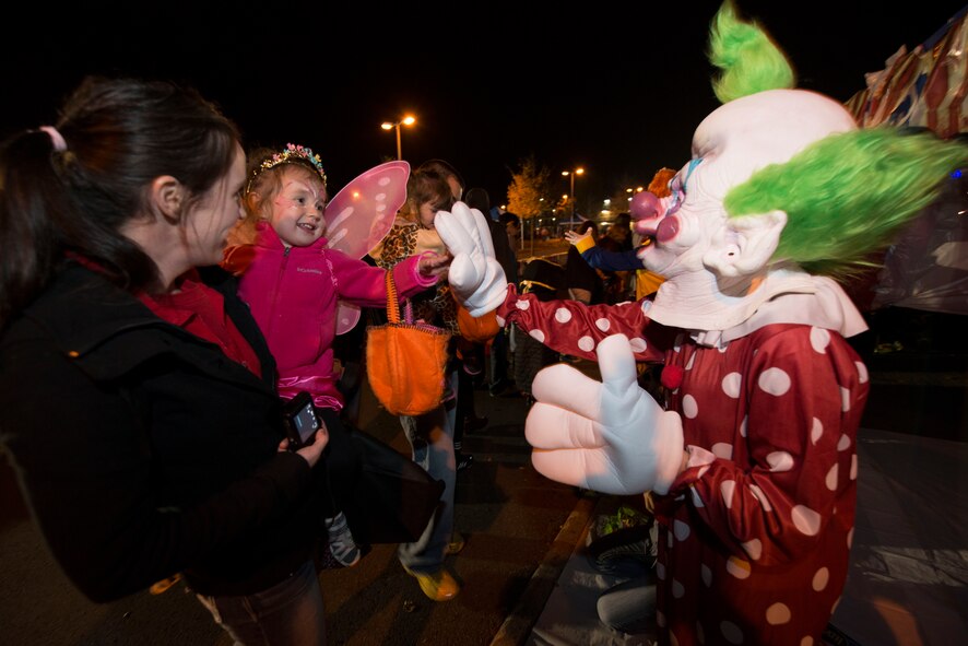Volunteers for Family Fright Night hand out candy to a trick-or-treater for “Trunk-or-Treat” at the Club Eifel parking lot on Spangdahlem Air Base, Germany, Oct. 30, 2015. “Trunk-or-Treat” allowed trick-or-treaters and their family members to safely get candy from the trunks of decorated vehicles. (U.S. Air Force photo by Staff Sgt. Christopher Ruano/Released)